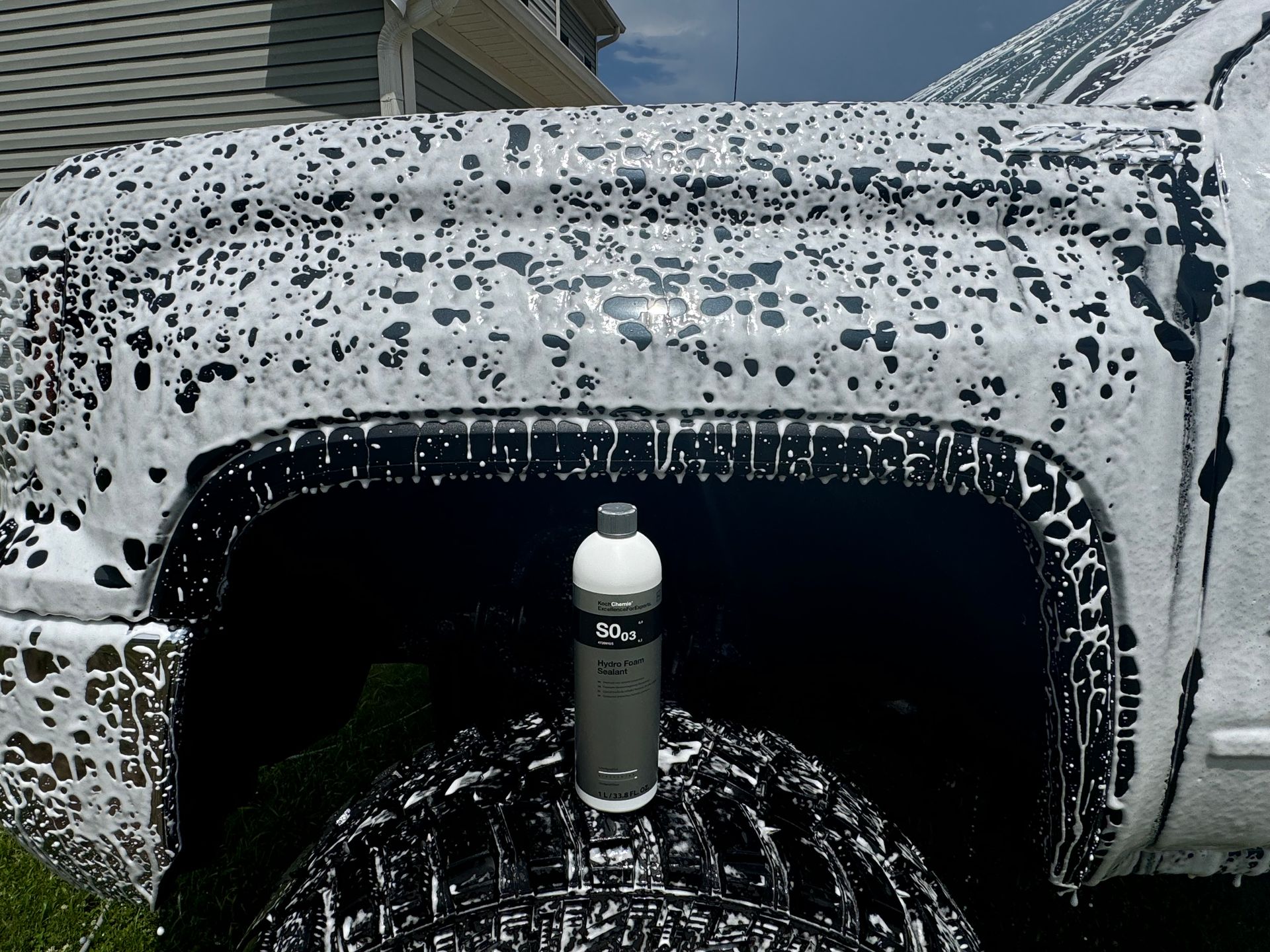 A gray sports car is parked in a driveway in front of a garage.