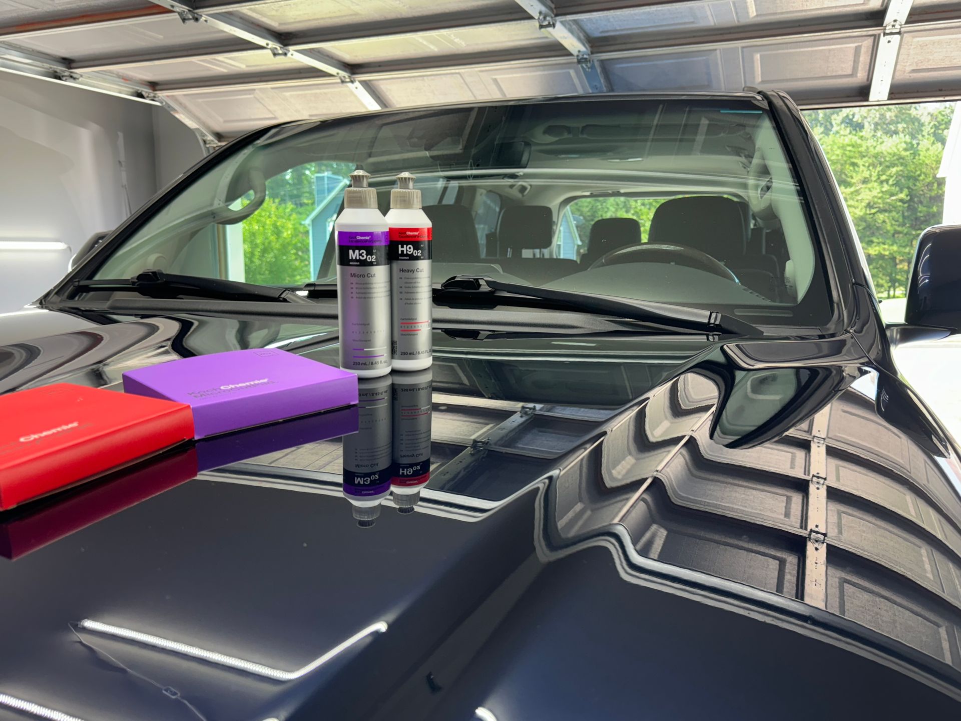 A black bmw x7 is parked on a brick driveway in front of a house.