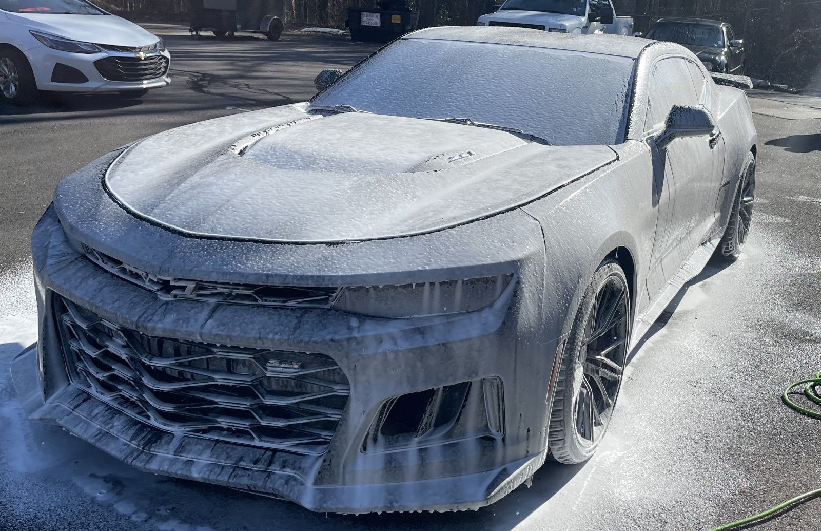 A corvette is covered in foam in a parking lot