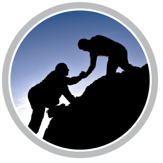 A silhouette of two people helping each other climb a mountain