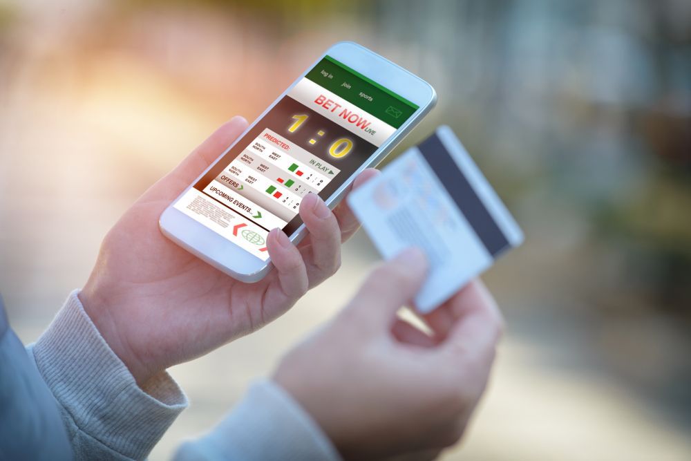 A person is holding a credit card and a cell phone.