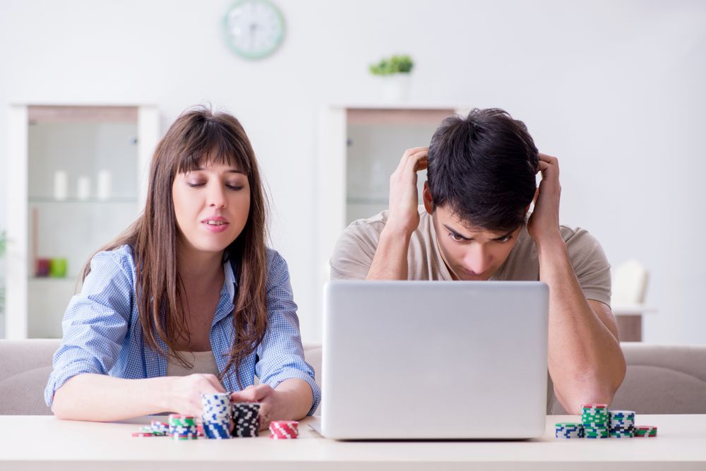 A man and a woman are sitting at a table with a laptop.