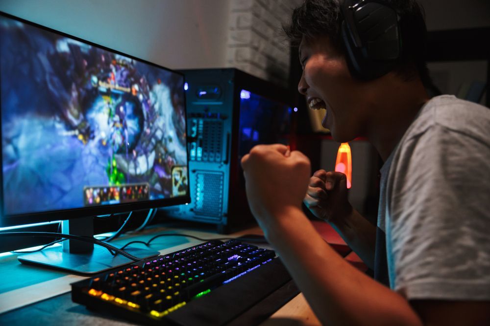 A man wearing headphones is playing a video game on a computer.