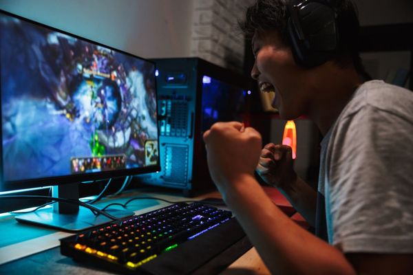 A man wearing headphones is playing a video game on a computer.
