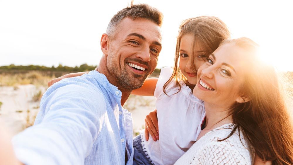 A family is taking a selfie on the beach.