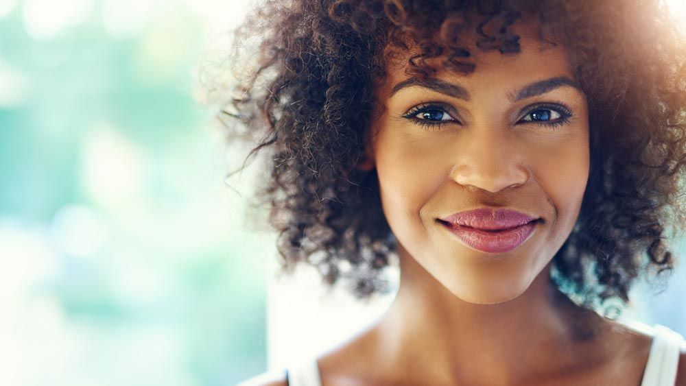 A woman with curly hair is smiling and looking at the camera.