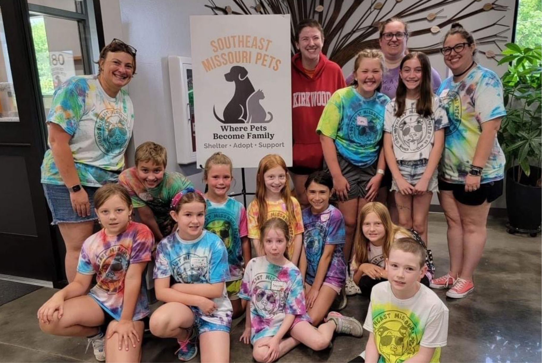 A group of children are posing for a picture in front of a sign.