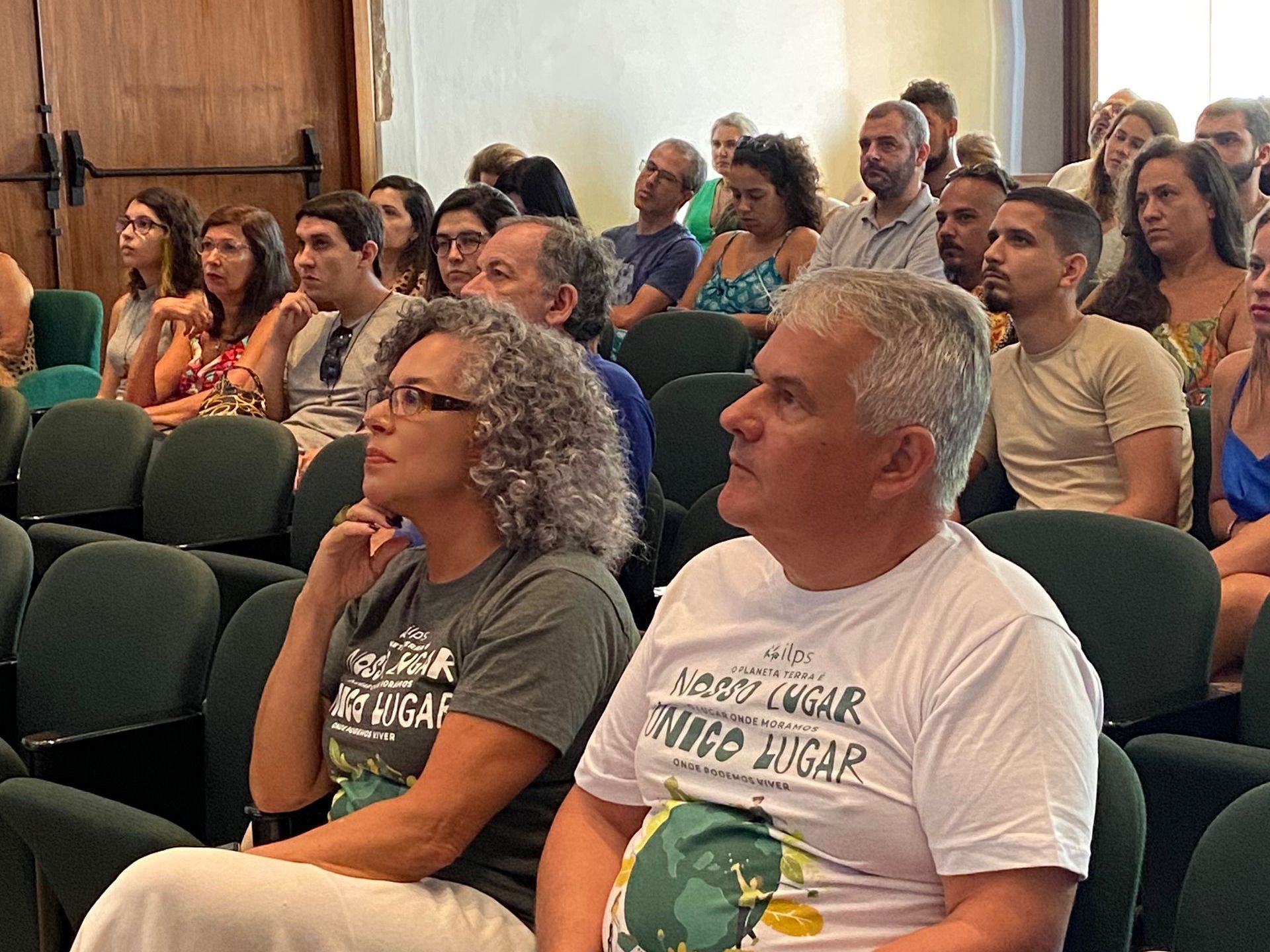 Um grupo de pessoas está sentado em uma sala de aula assistindo a uma apresentação.