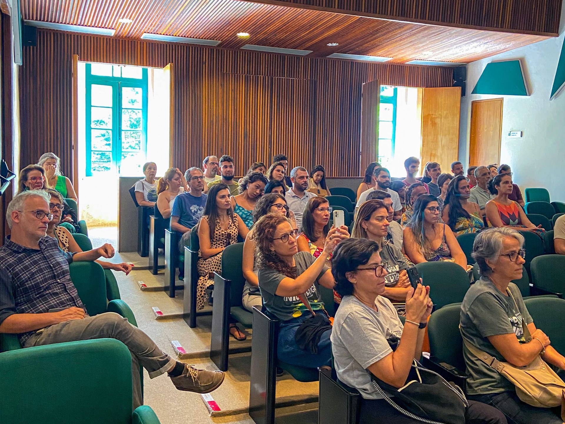 Um grande grupo de pessoas está sentado em uma sala de aula.