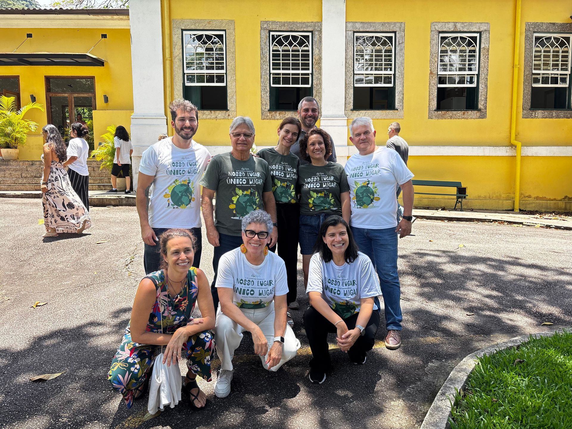 Um grupo de pessoas posa para uma foto em frente a uma tela de projetor.