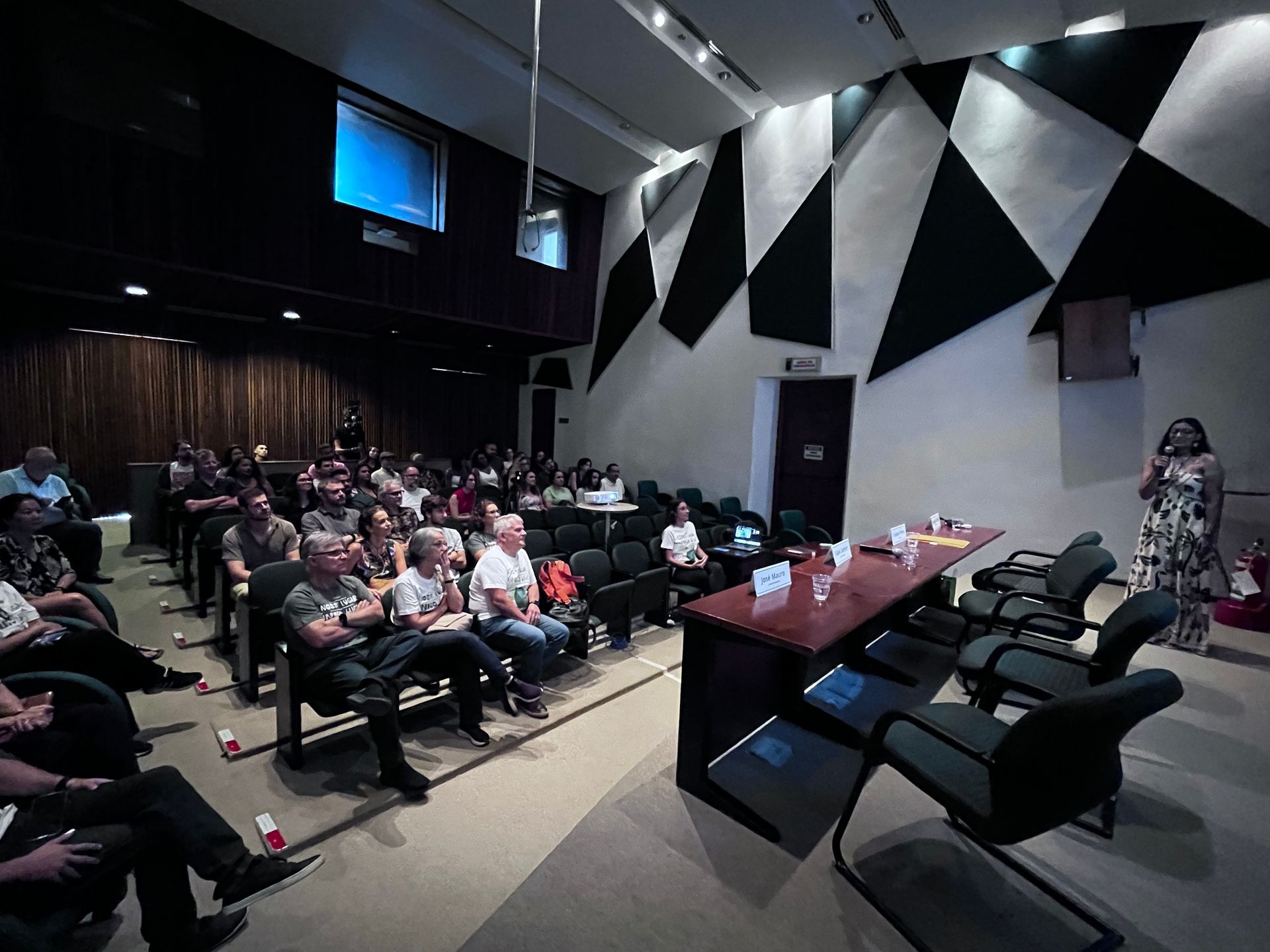 Um grupo de pessoas está sentado em uma sala de aula assistindo a uma apresentação.