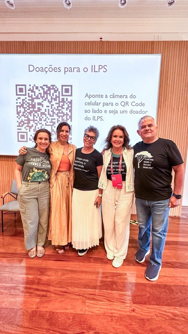 Um grupo de pessoas posa para uma foto em frente a uma tela de projetor.