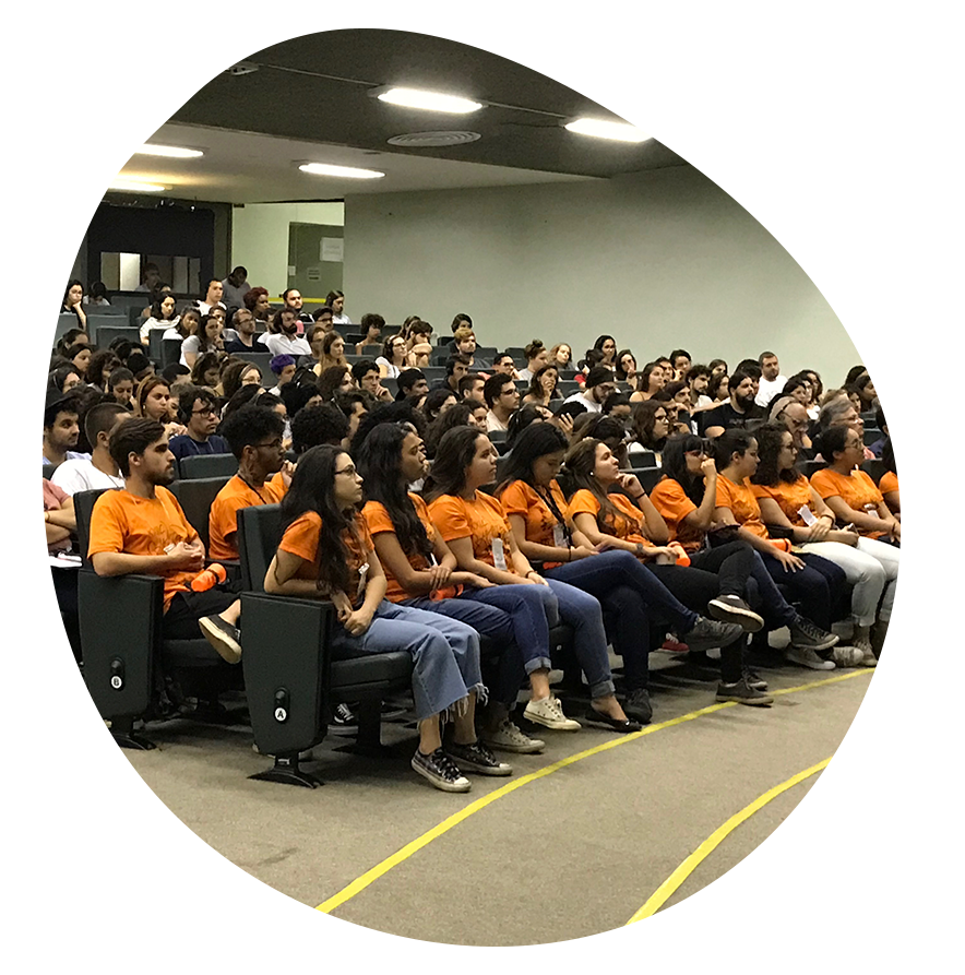 Um grande grupo de pessoas está sentado em uma sala de aula.