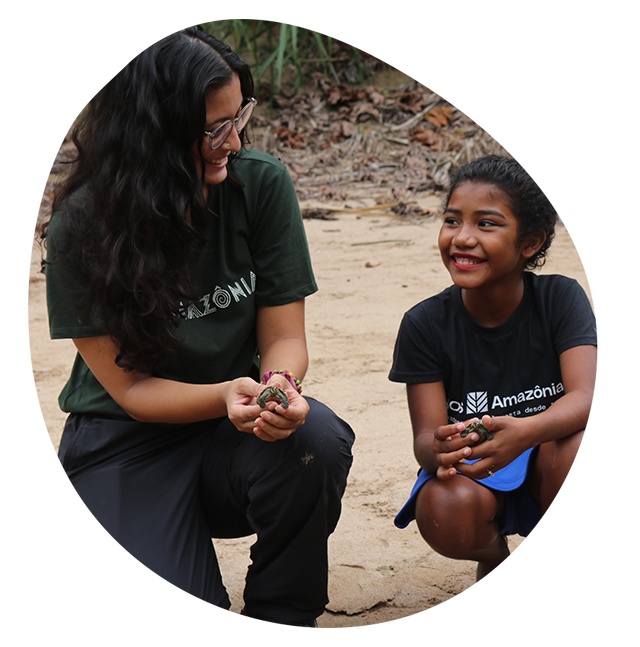Mulher e menina segurando pequenas tartarugas na areia;