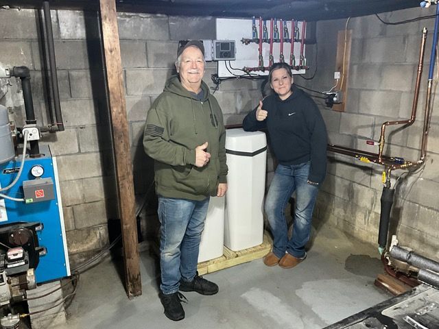 Two men are standing next to each other in a basement giving a thumbs up.