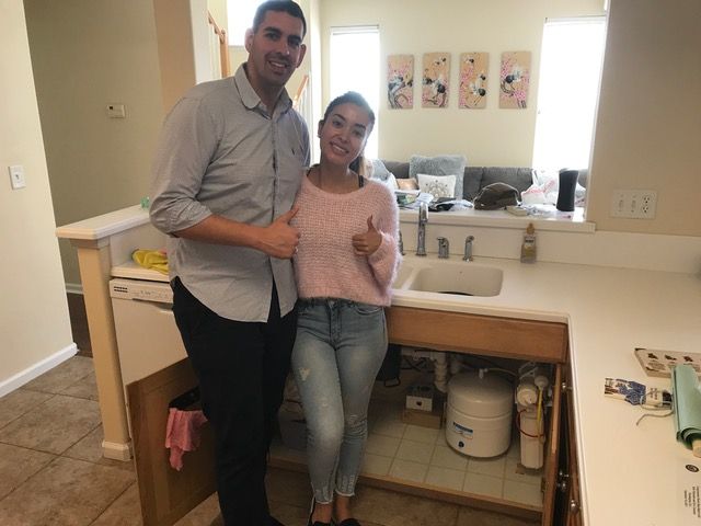 A man and a woman are posing for a picture in a kitchen.