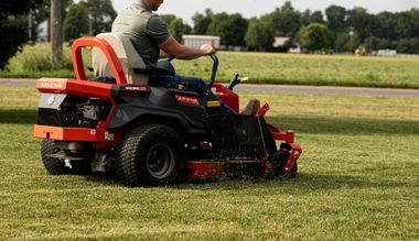 Red riding lawn mower cutting grass in a sunny field