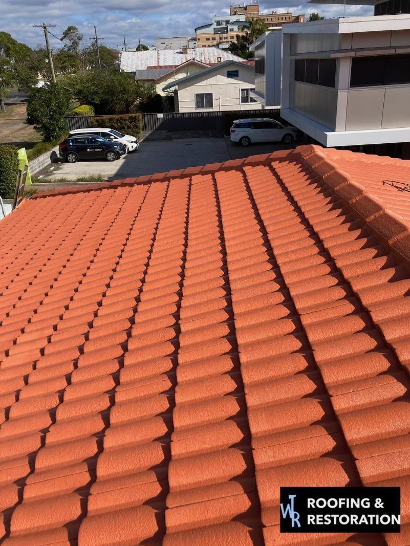 A red tiled roof with a sign that says roofing & restoration — Wayne Treasure Roofing & Restoration In Forster, NSW