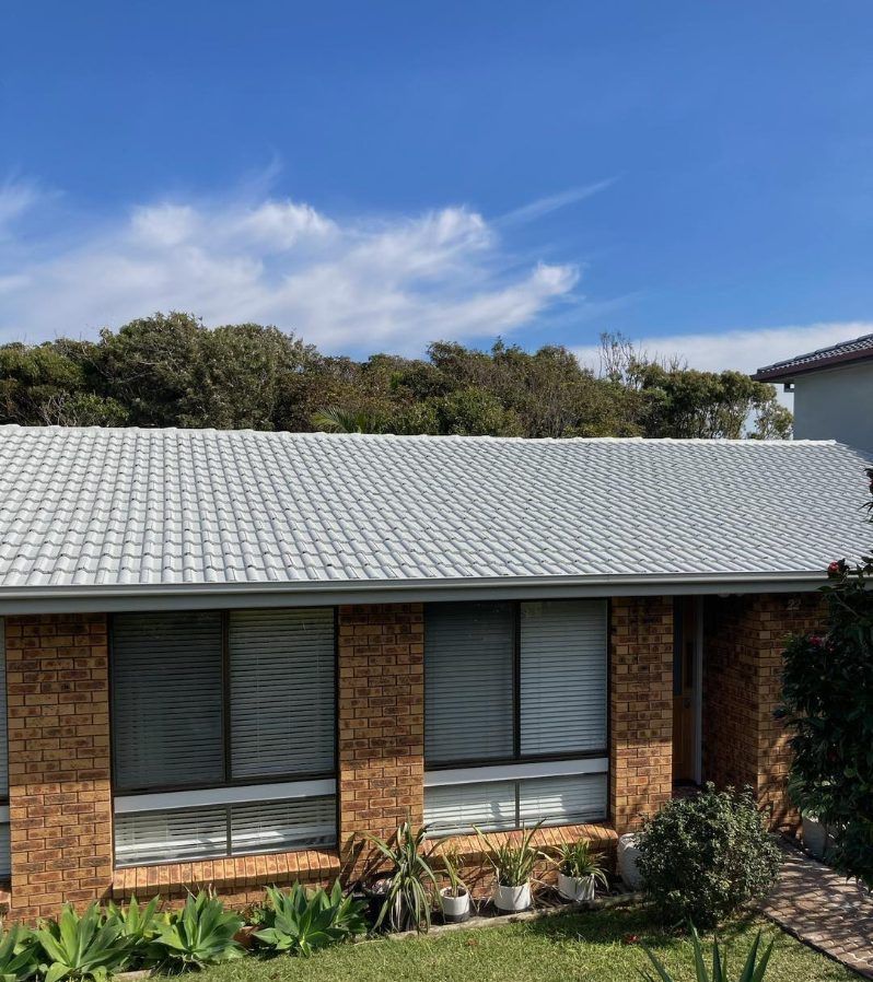 A brick house with a white roof and many windows — Wayne Treasure Roofing & Restoration In Taree, NSW