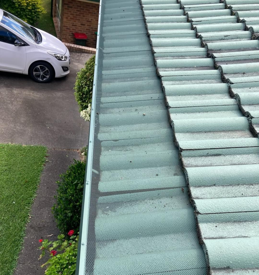 A white car is parked on the side of a roof next to a gutter. — Wayne Treasure Roofing & Restoration In Taree, NSW