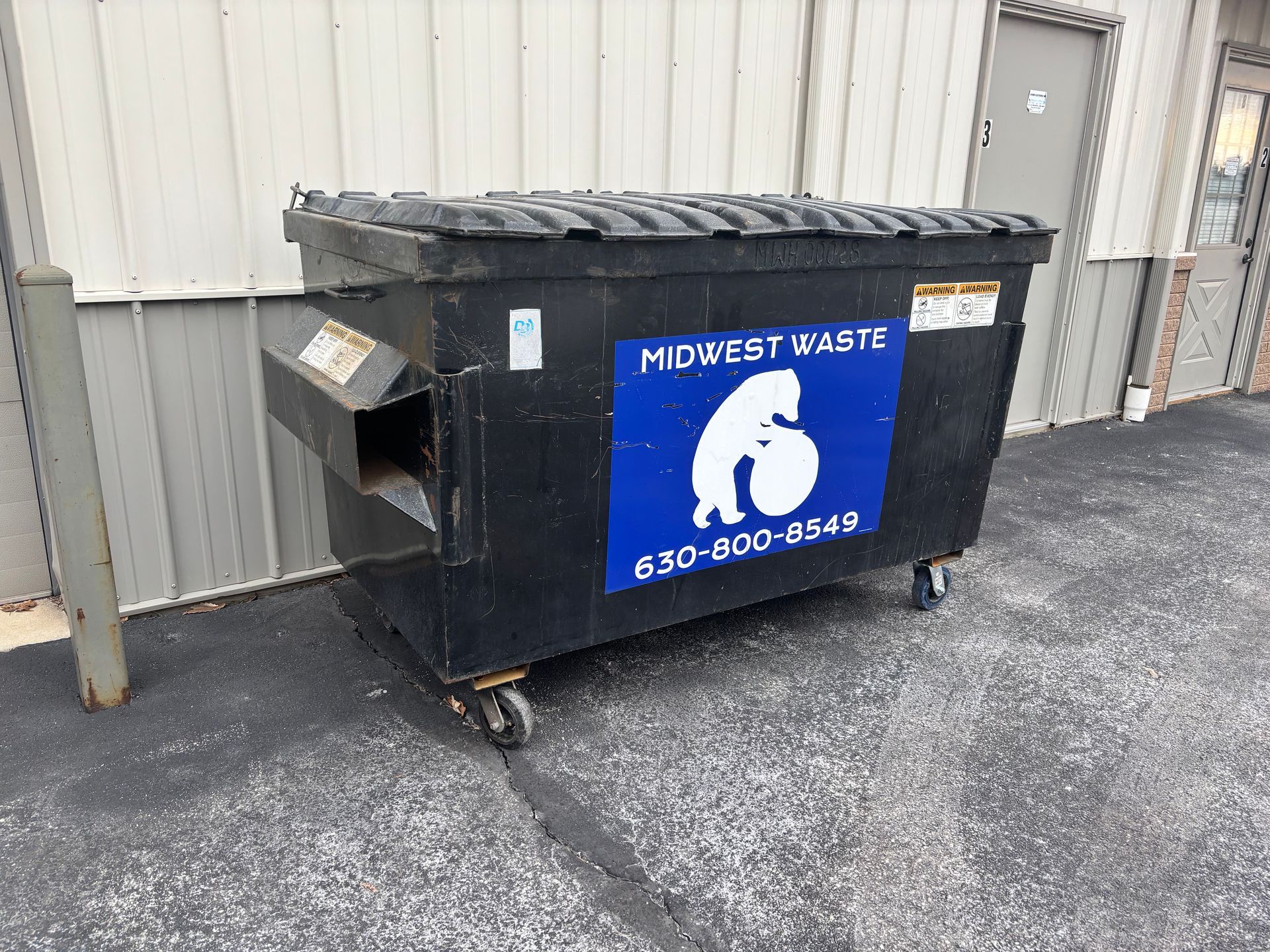 A black industrial dumpster with a blue 