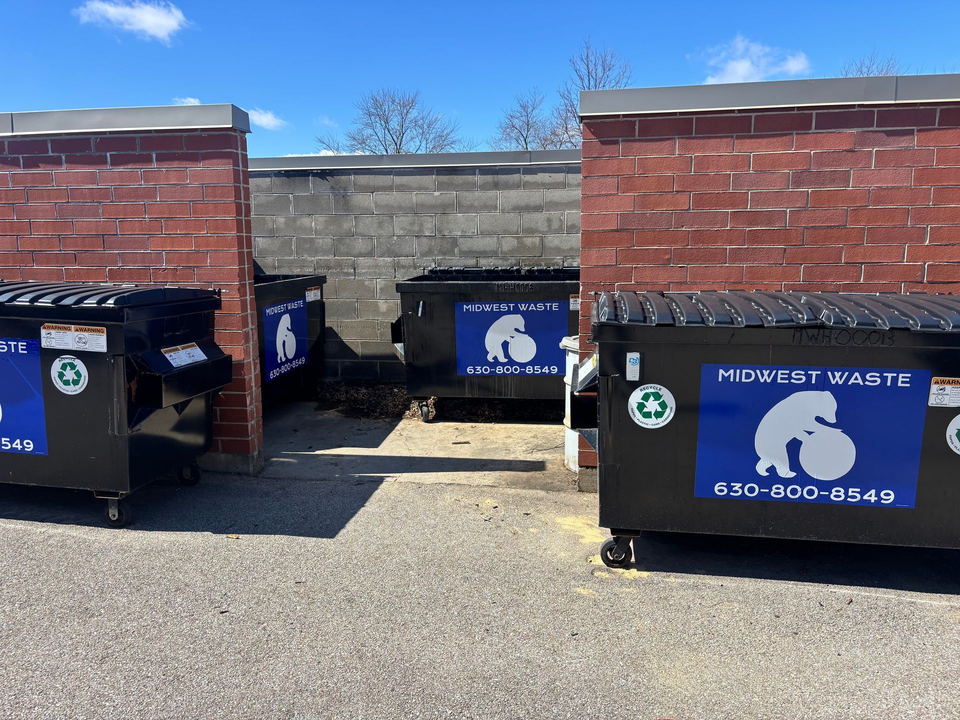 Volunteers wearing reflective vests and gloves collect litter into black plastic bags in a park.