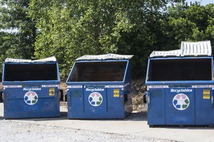 Three blue recycling bins are lined up next to each other