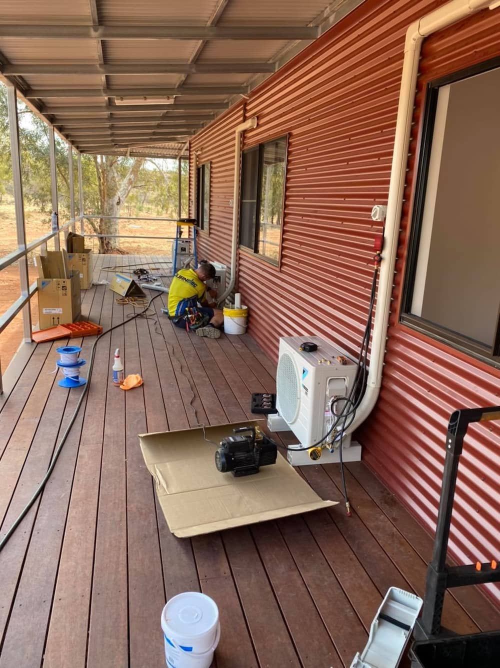 Man is Working on an Air Conditioner on the Porch of a House β AJ Services in Alice Springs, NT