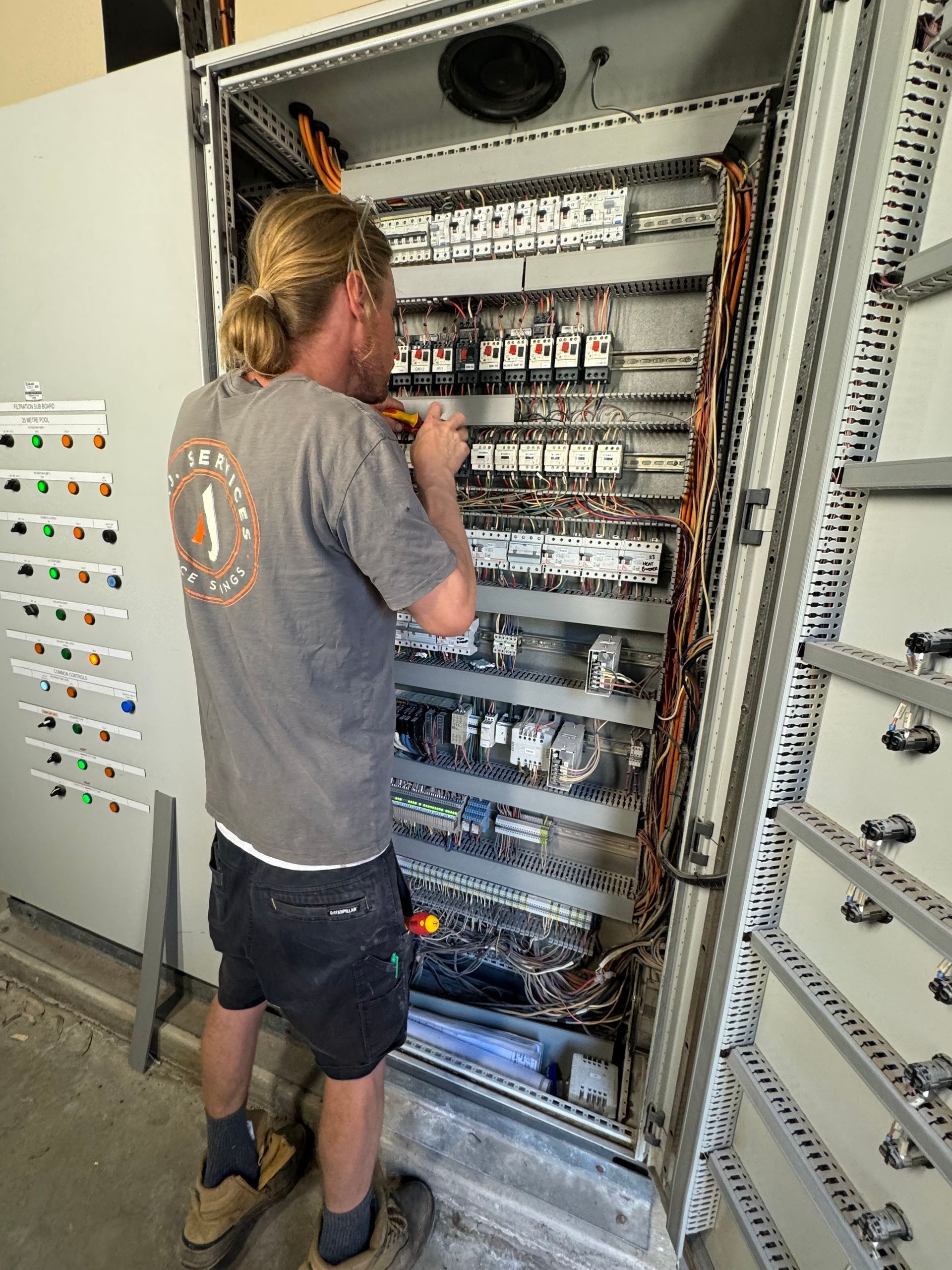 A man is working on a large electrical box — AJ Services in Alice Springs, NT