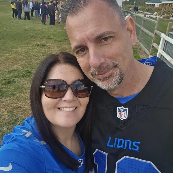 Selfie of two smiling fans in Lions gear at an outdoor field