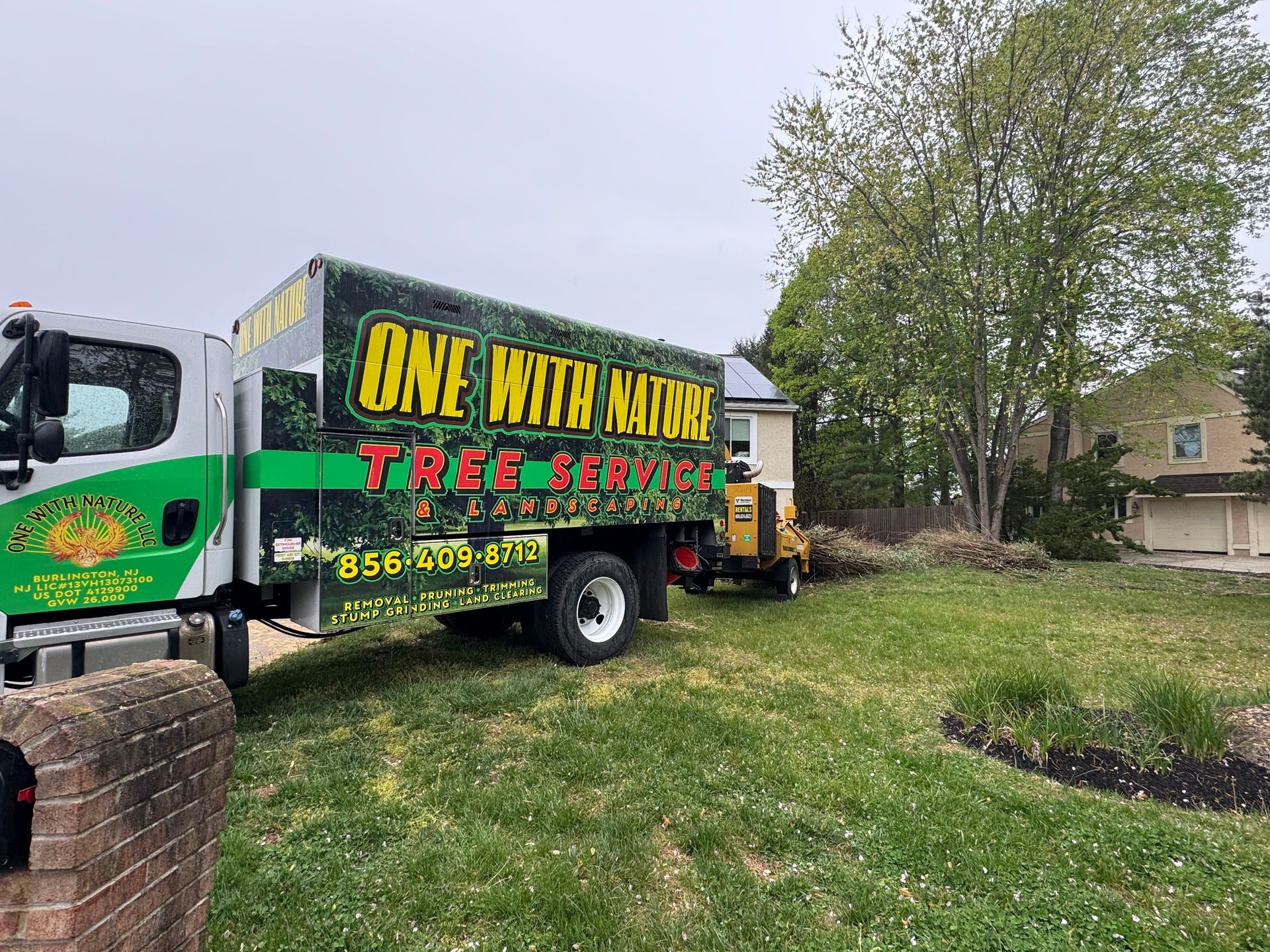 Food truck with bright “One Hot Nation” signage parked on a grassy lawn beside a tree and house.