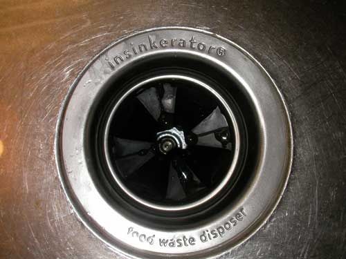 A close up of a sink drain with a food waste disposer on it.