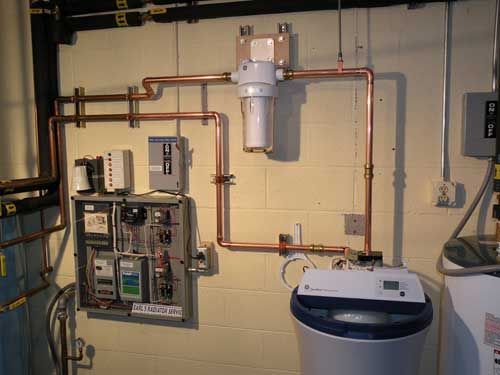 A copper pipe system is installed in a basement next to a washer and dryer.