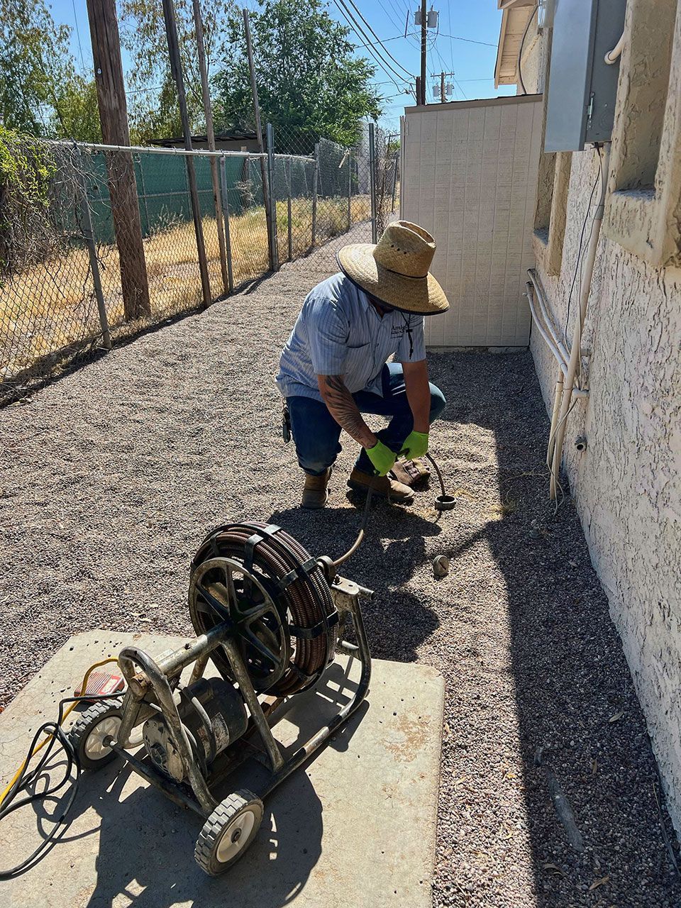 A man in a hat is kneeling down next to a machine.
