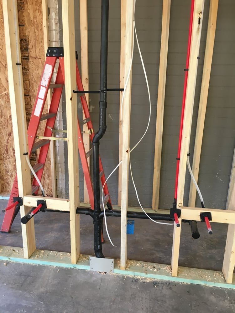 A ladder is sitting next to a pipe in a room under construction.