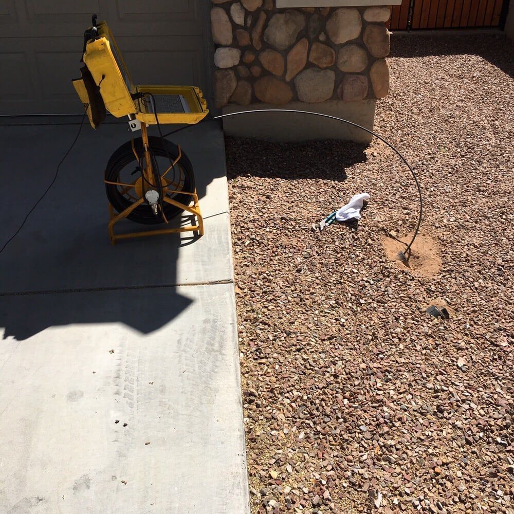 A yellow machine is sitting on the sidewalk next to a stone wall.