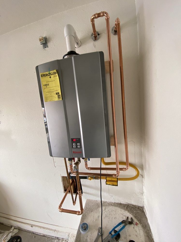 A water heater is hanging on a wall next to copper pipes.