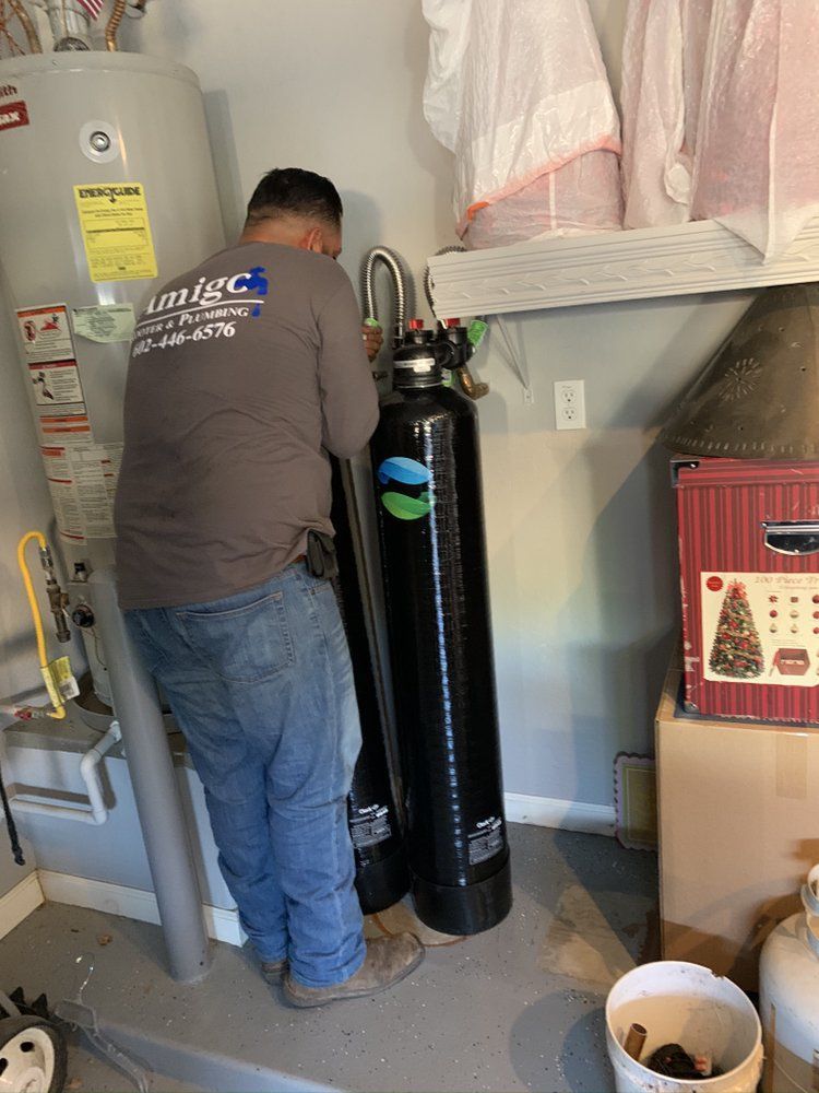 A man is working on a water heater in a garage.