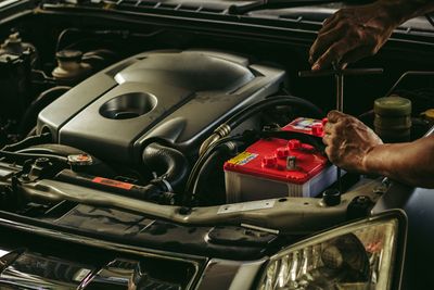 A man is working on the engine of a car with a wrench.