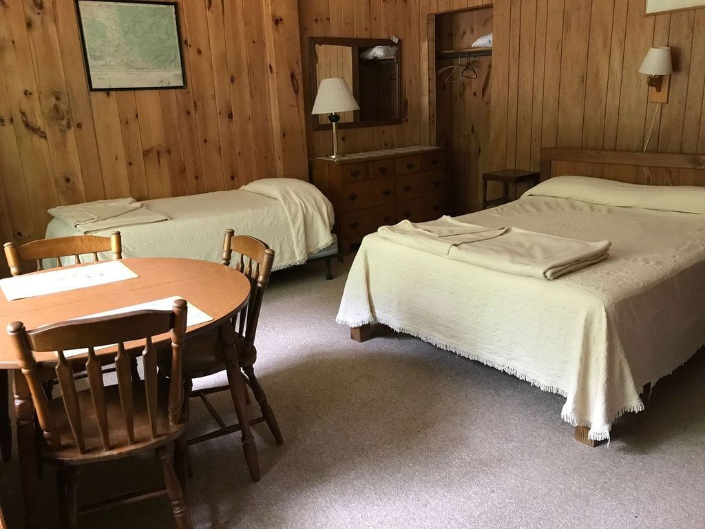 a hotel room with two beds , a table and chairs .