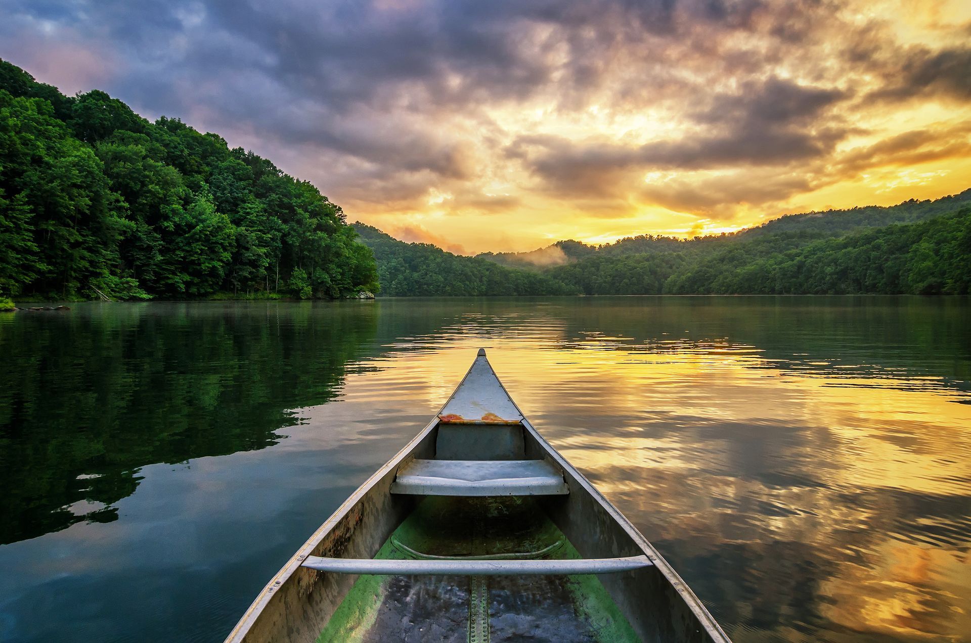 A canoe is floating on a lake at sunset.