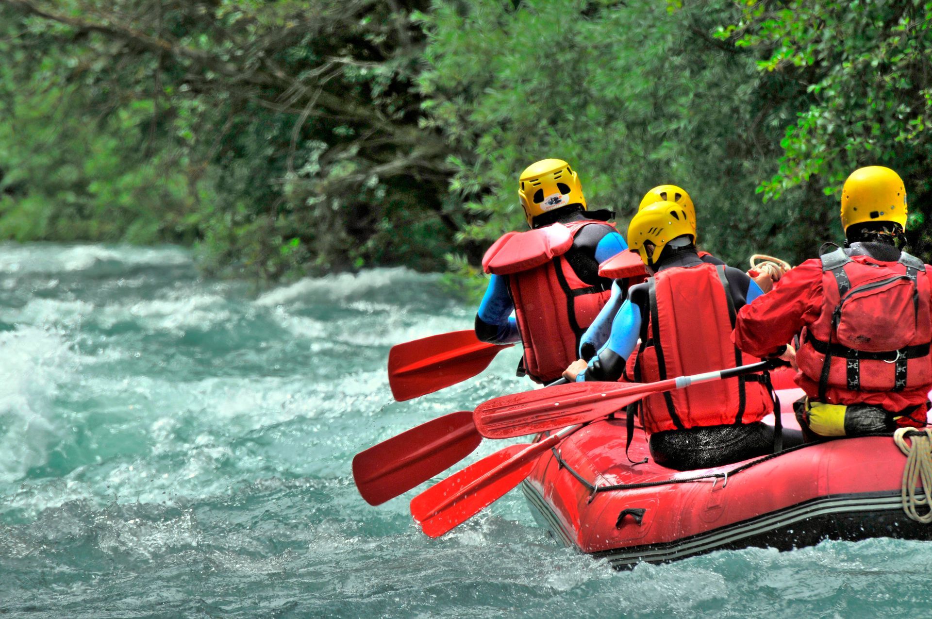 A group of people are rafting down a river in a red raft.