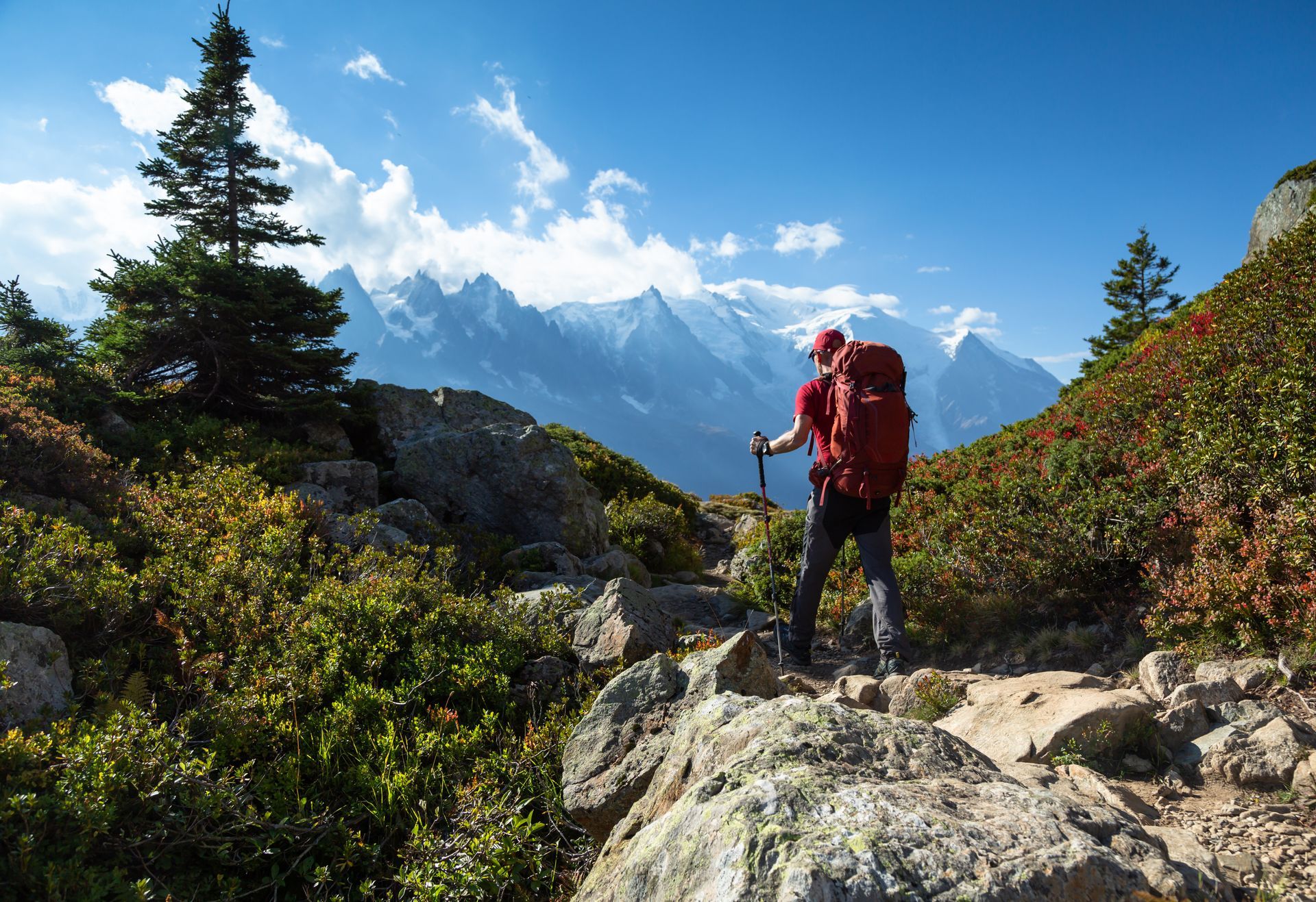 A man with a backpack is hiking on a trail in the mountains.