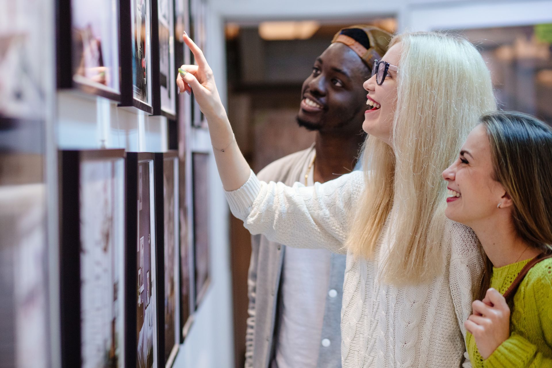 A group of people are looking at pictures on a wall in a museum.