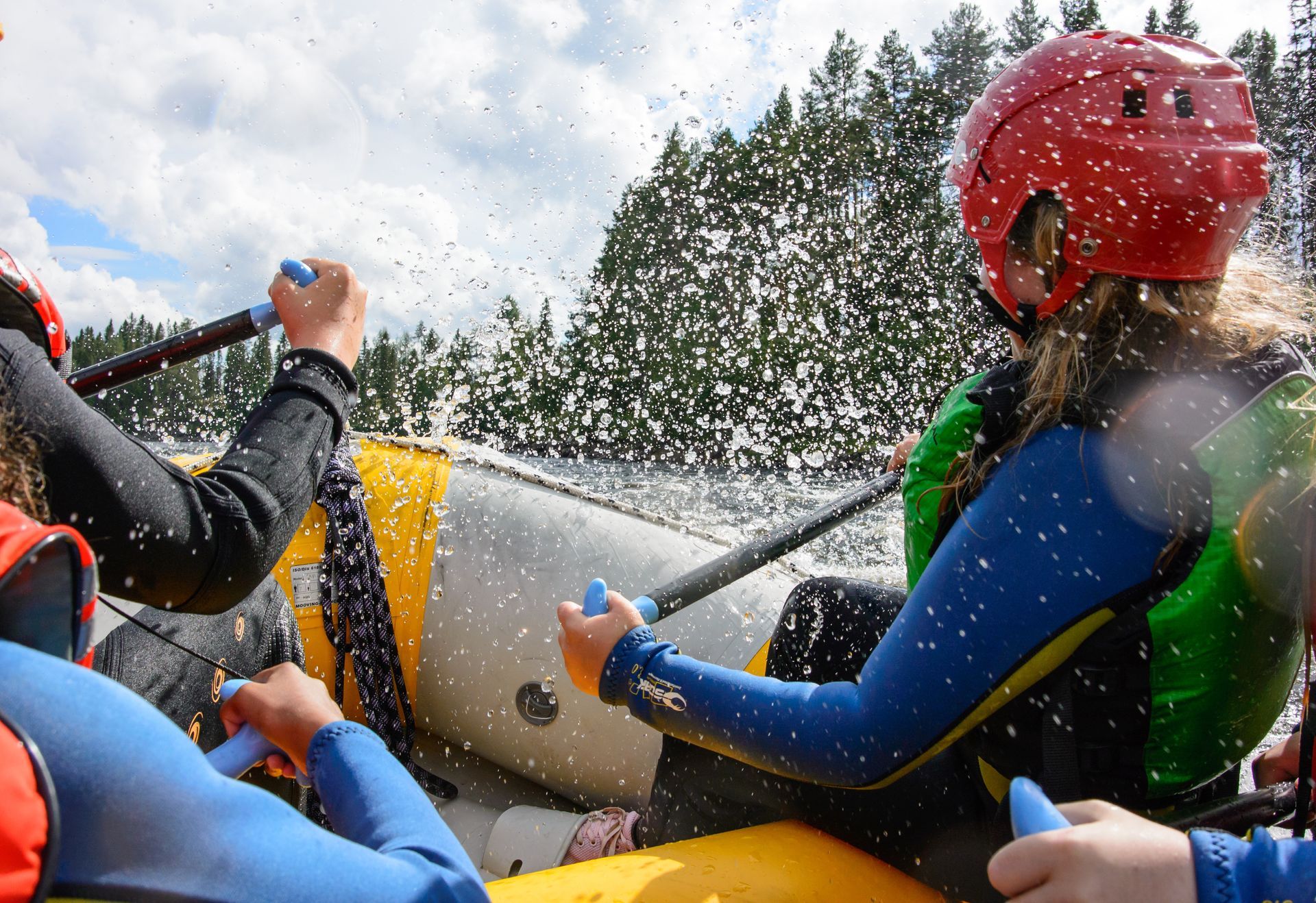 A woman in a red helmet is sitting in a raft with other people