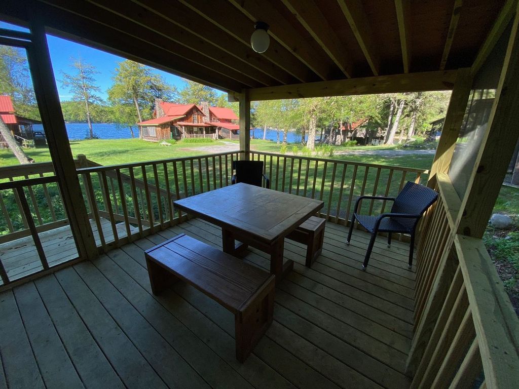 there is a table and chairs on the porch of a cabin .