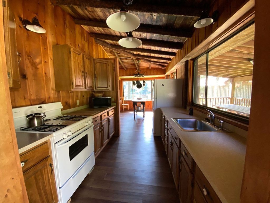 a long kitchen with a stove , sink , and cabinets .