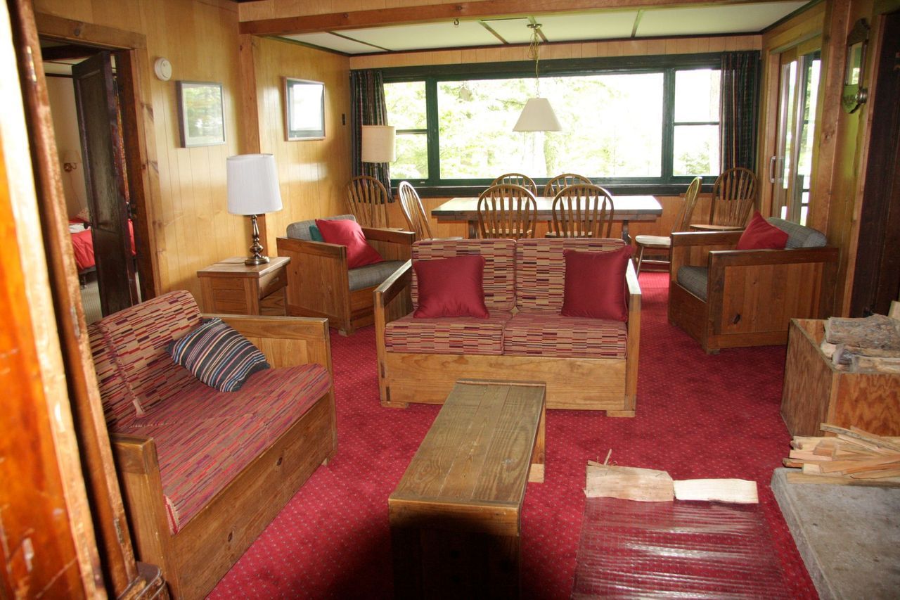 a living room with wooden furniture and a red carpet