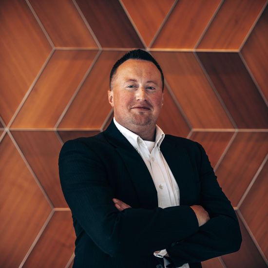 A woman is sitting at a desk with a laptop and a vase of flowers.