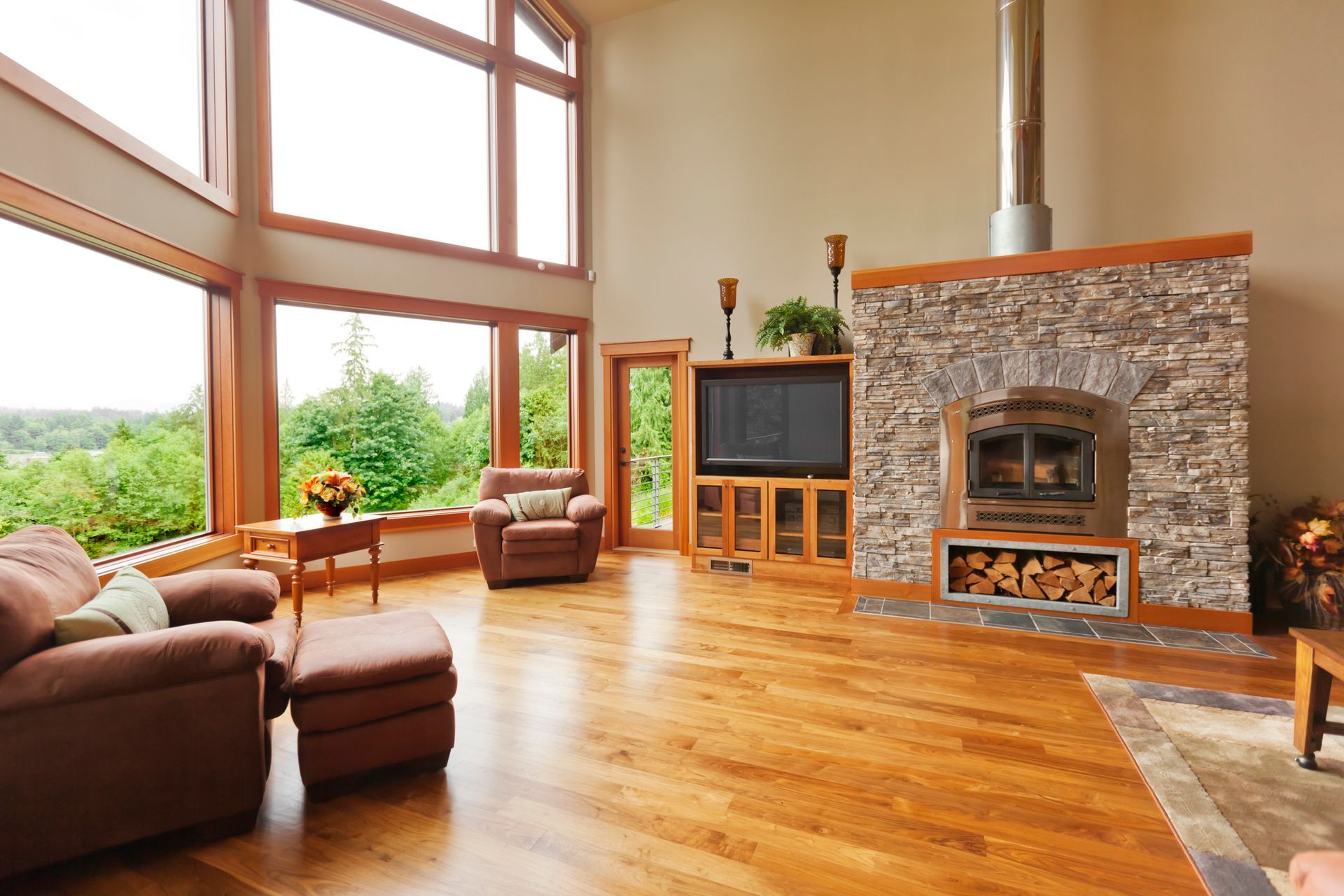Spacious living room with hardwood flooring, stone fireplace, and floor-to-ceiling windows.] 